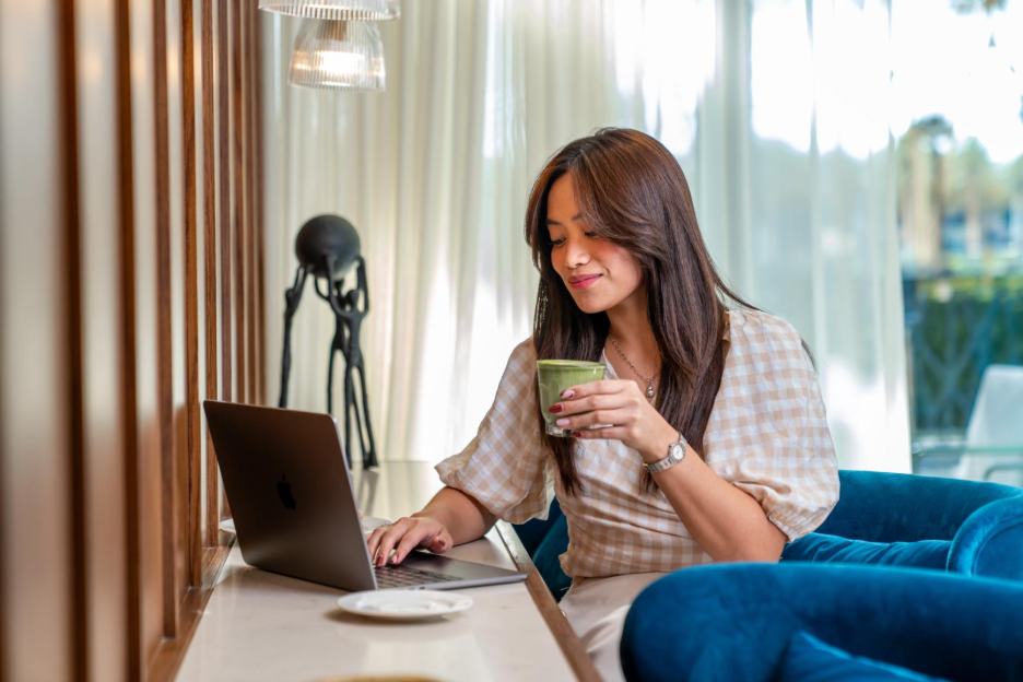 Woman at laptop in cafe drinking matcha drink