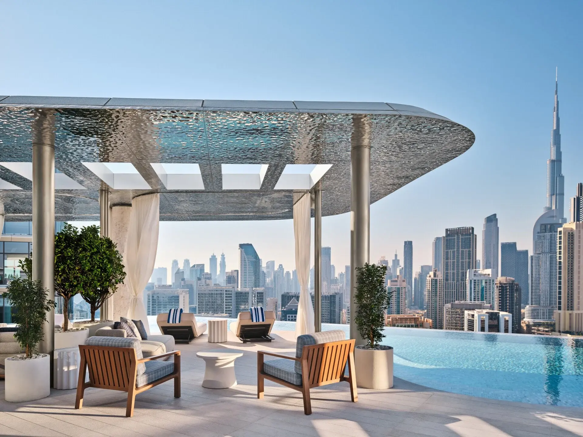 Stylish rooftop lounge and infinity pool at a luxury hotel in Dubai with skyline and Burj Khalifa views, highlighting premium guest experience and tranquil F&B settings. 